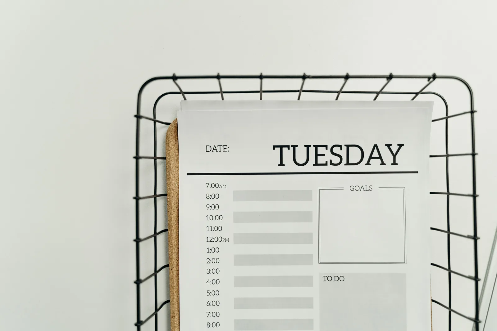 Top view of a minimalist Tuesday planner on a wire basket for organization and scheduling. Add business days: three start conventions and fifteen worked cases excluding the start