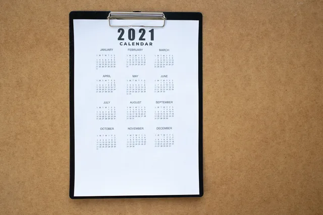 A 2021 calendar clipped to a black clipboard on a brown surface. Ideal for planning or scheduling visuals. The open-day formula with rest-day sets: five weekend conventions and cross-border spans