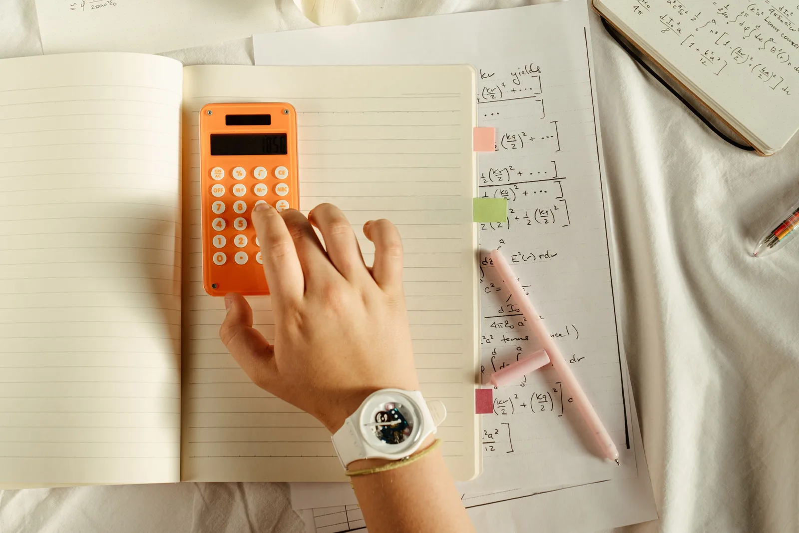 A student calculates math equations using an orange calculator and notebook for study. Notes on working days per month in Excel: NETWORKDAYS, EOMONTH and month edges